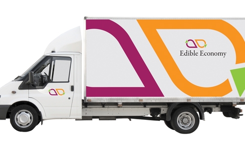 white panel truck with large graphic of Edible Economy logo close-cropped to fill one side.
