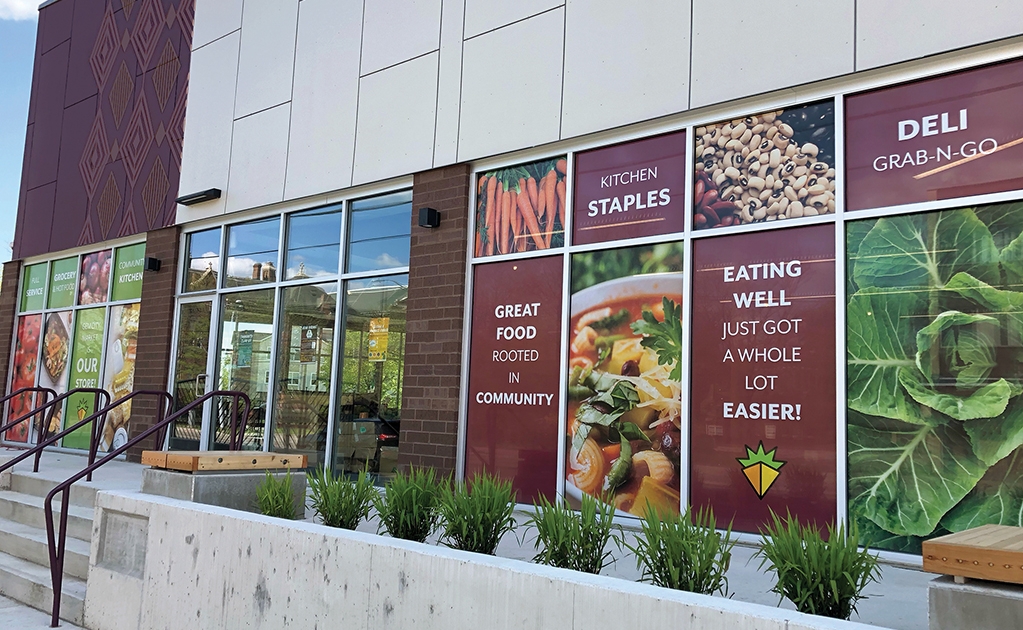 Exterior view of Gem City Market, Dayton OH. Facade is made up primarily of large floor-to-ceiling windows which are filled with bright, simple food photos and branded messaging in each panel
