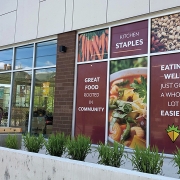 Exterior view of Gem City Market, Dayton OH. Facade is made up primarily of large floor-to-ceiling windows which are filled with bright, simple food photos and branded messaging in each panel